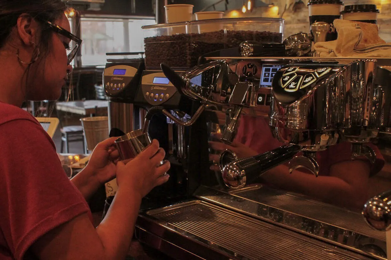 A barista steaming milk at the espresso bar