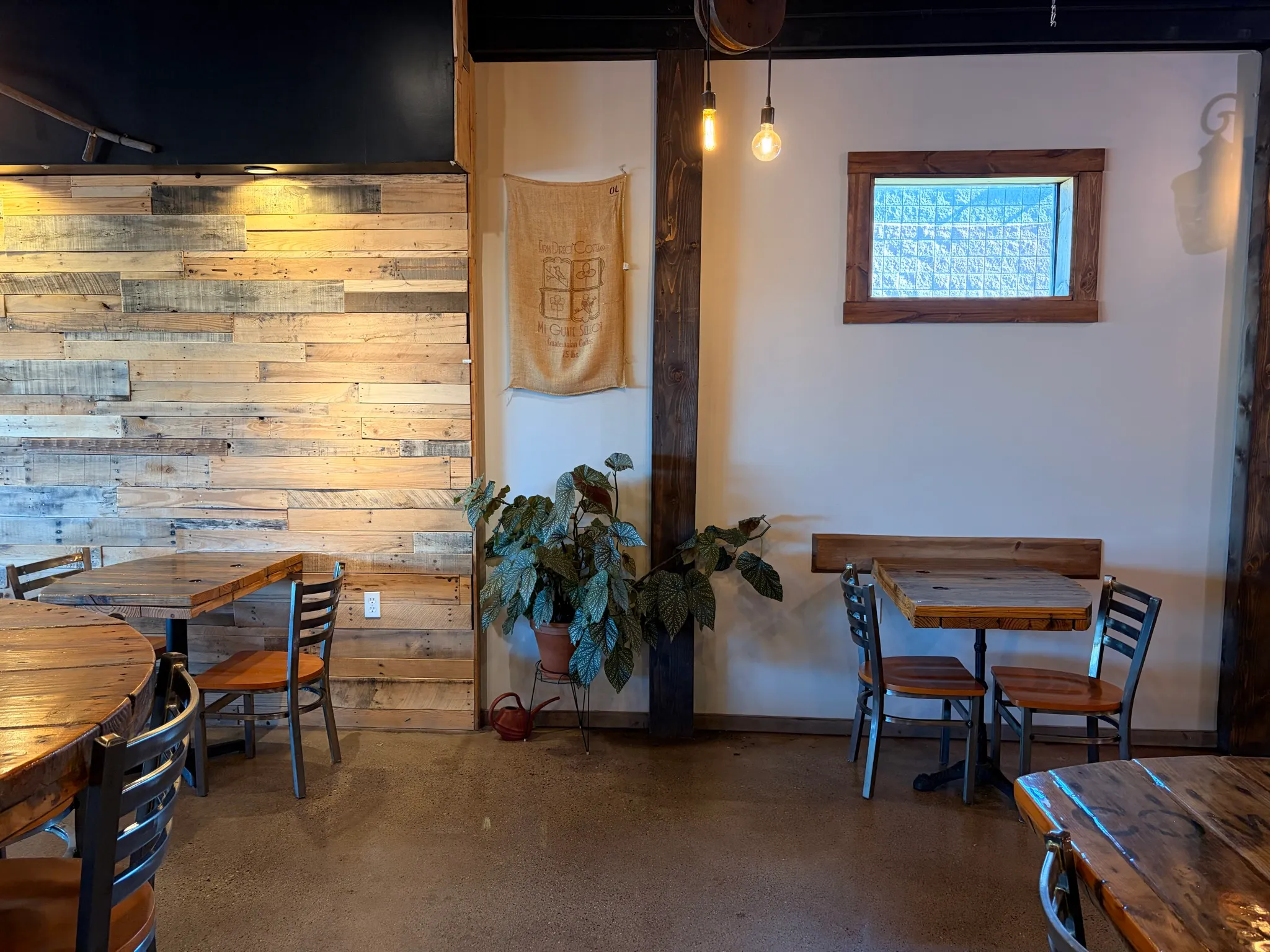 Two-top tables against the reclaimed pallet wall in the main room at The Brew Cafe