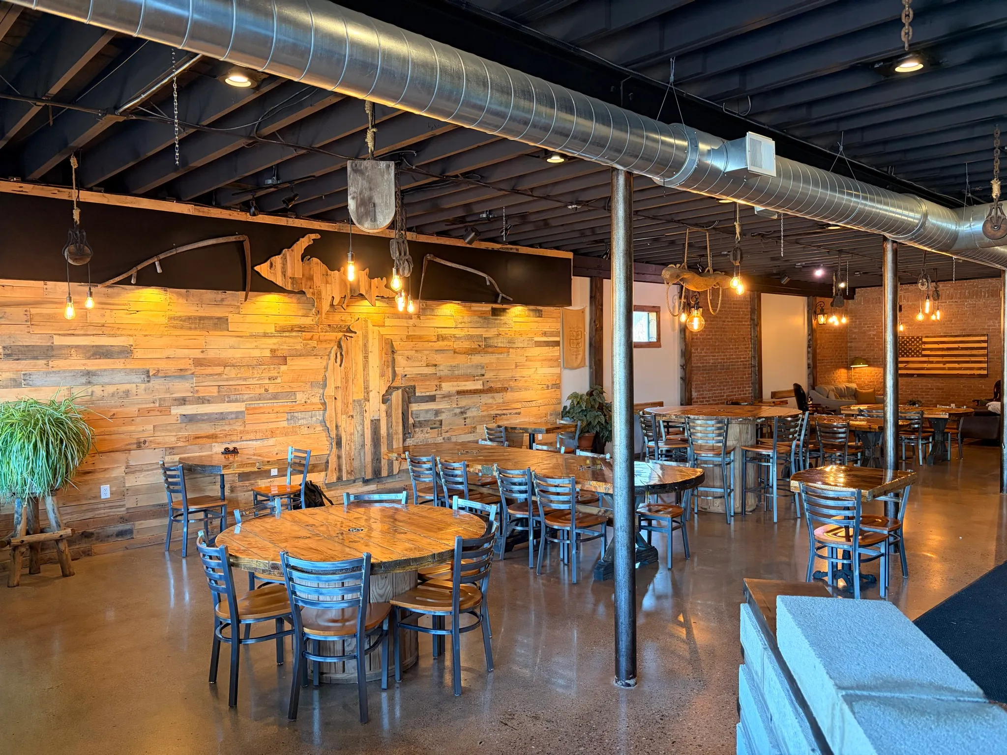 The main room at The Brew Cafe, with cable-spool tables and the Michigan wall built from reclaimed pallet wood