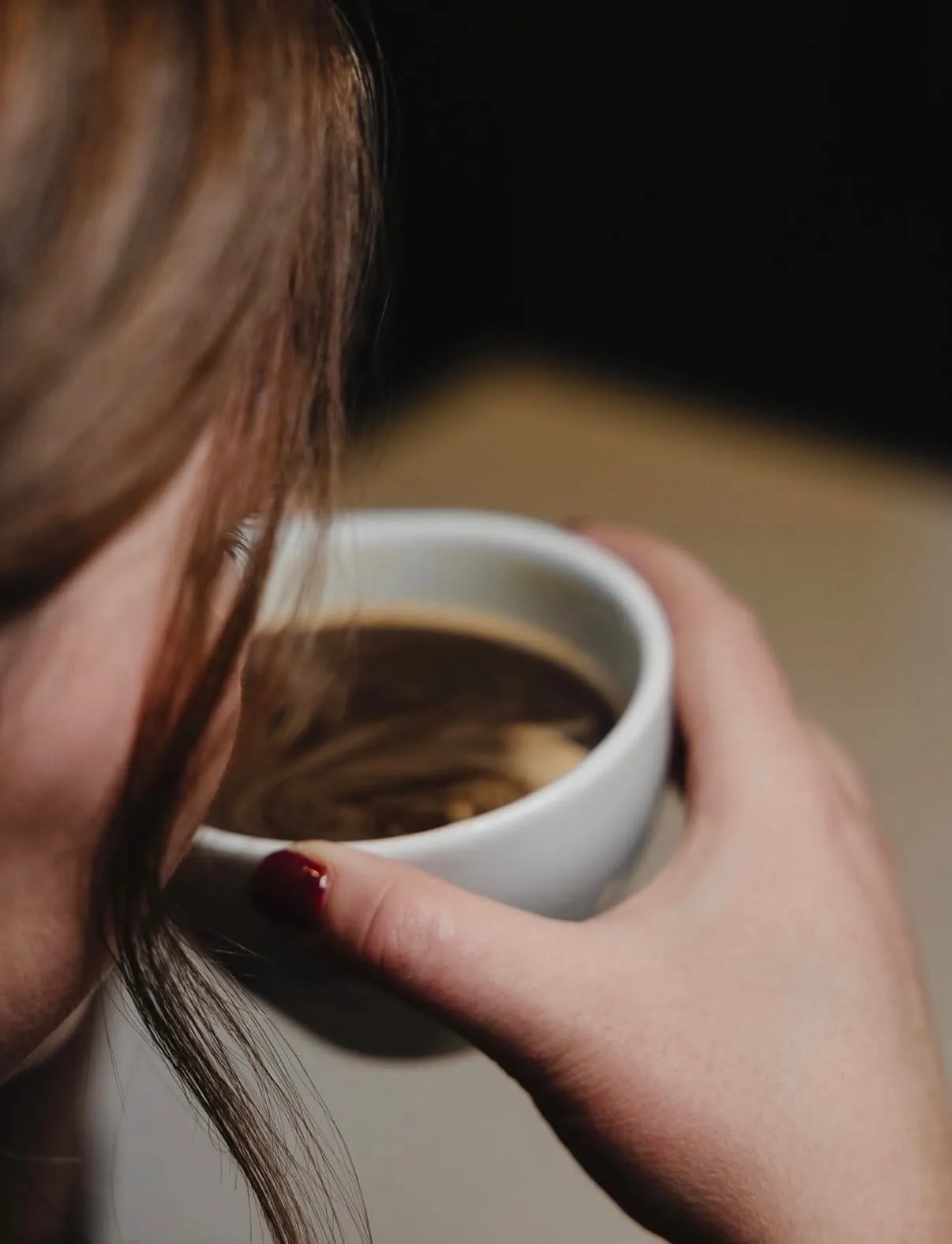 A cup of coffee held in both hands at a table